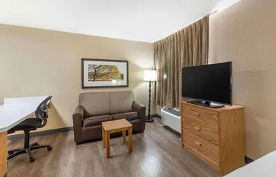 a hotel room with a chair and a flat screen tv at Extended Stay America Select Suites - Orlando - Lake Mary - 1040 Greenwood Blvd in Lake Mary