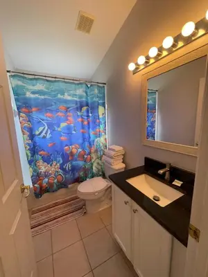 a bathroom with a fish shower curtain and a toilet at Cinderellas Castle in Kissimmee