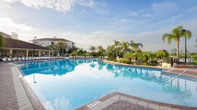 a large swimming pool with chairs and palm trees at Chantilly Condo - closer to Disney and Universal in Orlando