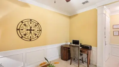 a home office with a desk and a clock on the wall at Merlyns Magic Condo - closer to Disney in Orlando