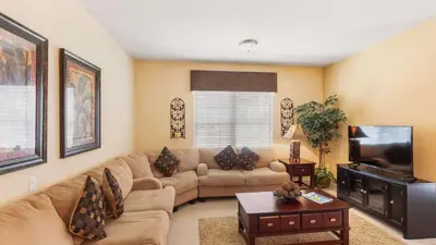 a living room with a couch and a flat screen tv at Merlyns Magic Condo - closer to Disney in Orlando