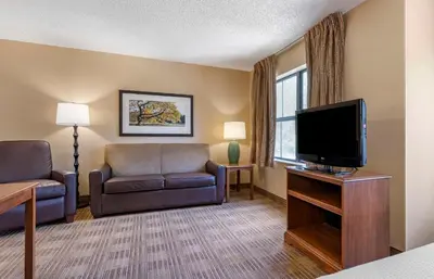 a living room with a flat screen tv and chairs at Extended Stay America Suites - Orlando - Maitland - 1776 Pembrook Dr in Orlando