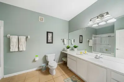 a bathroom with a toilet and a sink and a mirror at Deluxe 3 Bedroom Apartment 404 in Orlando