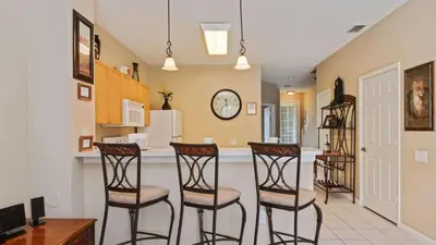 a kitchen with two bar stools and a counter at Minnies Townhouse in Windsor Palms Resort in Kissimmee