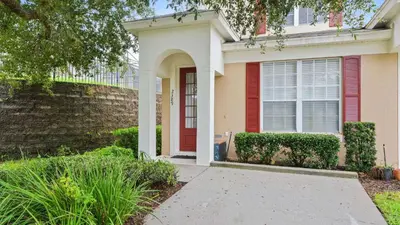 a home with a red door and a brick wall at Minnies Townhouse in Windsor Palms Resort in Kissimmee