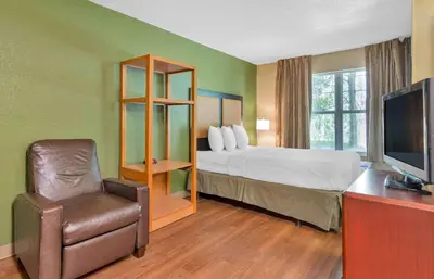 a hotel room with a bed and a chair at Extended Stay America Select Suites - Orlando - Maitland - Summit Tower Blvd in Orlando