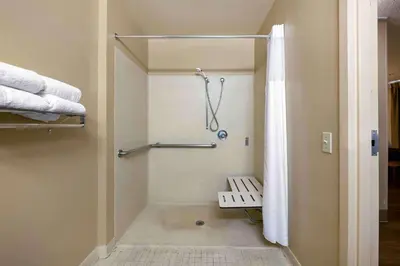 a bathroom with a shower with a bench and towels at Extended Stay America Suites - Orlando - Convention Center - 6443 Westwood in Orlando