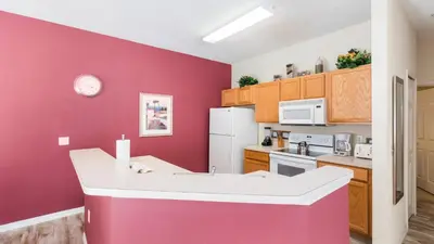 a kitchen with a pink wall and a white refrigerator at Bikini on the Beach at Terra Verde Resort in Kissimmee