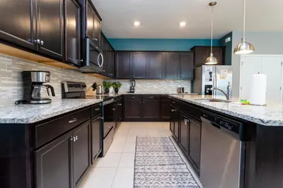 a kitchen with dark wood cabinets and marble counter tops at Encantada Rose - a 4 bed townhouse near Disney in Kissimmee