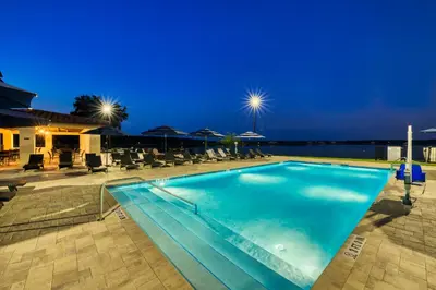 a swimming pool at night with chairs and umbrellas at Siena at Bella Collina in Montverde