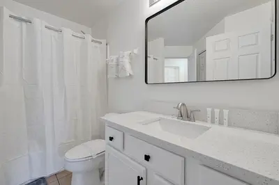a bathroom with a sink and a toilet and a mirror at Bikini Bottom - 4 bed Disney pool home in Kissimmee