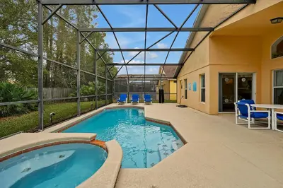 a swimming pool with blue chairs and a table at Castaway Getaway - Very popular 4 bed family pool home on Terra Verde Resort - close to Disney World in Kissimmee