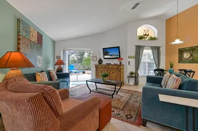 a living room with two blue couches and a tv at Castaway Getaway - Very popular 4 bed family pool home on Terra Verde Resort - close to Disney World in Kissimmee
