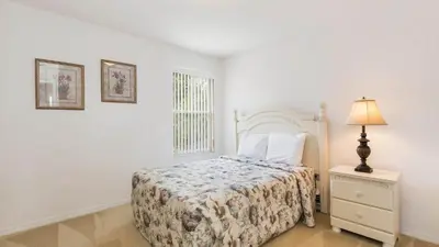 a bedroom with a bed and a lamp and a window at Lucky Charm - Budget-friendly 5 bed vacation home, close to Disney World in Kissimmee