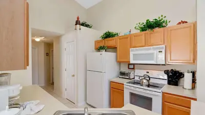 a kitchen with a white refrigerator and wooden cabinets at Waterside Villa - Family 4 bed Emerald Island Resort pool home that's close to Disney World in Kissimmee