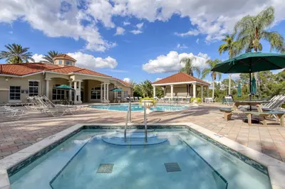 a pool at a resort with a picnic table and an umbrella at Waterside Villa - Family 4 bed Emerald Island Resort pool home that's close to Disney World in Kissimmee