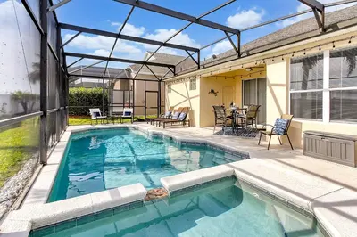 a swimming pool with a patio with a table and chairs at Sunshine Station - Spacious 4 bed Windsor Palms resort home that's close to Disney in Kissimmee