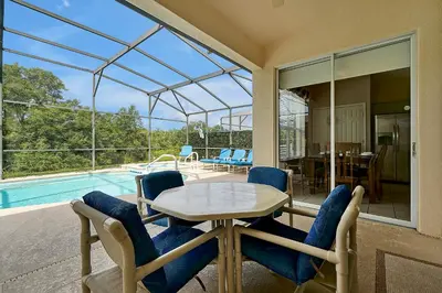 a patio with a table and chairs and a pool at Disney Magic Vacation - A fabulous 4 bed family pool home on Windsor Palms Resort - close to Disney World in Kissimmee