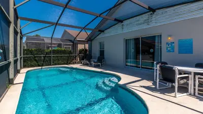 a swimming pool with a table and chairs next to a building at Rhapsody Palms - Family 4-bed pool home that's close to Disney in Kissimmee