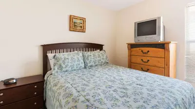 a bedroom with a bed and a tv on a dresser at Rhapsody Palms - Family 4-bed pool home that's close to Disney in Kissimmee