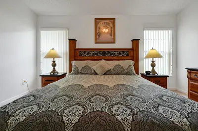 a bedroom with a large bed and two windows at Neptunes Retreat - 4 bed close to Disney in Kissimmee