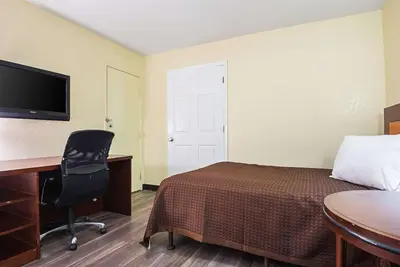 a room with a bed and a desk and a computer at Rodeway Inn Kissimmee - Orlando Maingate West - Free Theme Park Shuttle in Orlando