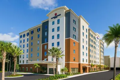 an image of a hotel with palm trees in front of it at Candlewood Suites - Orlando - Lake Buena Vista by IHG in Orlando