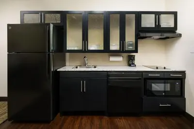 a black kitchen with a sink and a refrigerator at Candlewood Suites - Orlando - Lake Buena Vista by IHG in Orlando