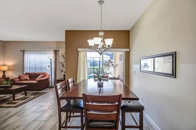 a dining room with a table and chairs and a couch at F - New 4 Bedroom Home - 5 Miles to Disney - Free Water Park - Private Pool in Kissimmee