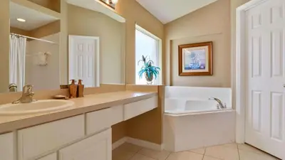 a bathroom with a sink and a tub and a mirror at Shooting Star - Family friendly 4 bed pool home on Emerald Island Resort - close to Disney World! in Kissimmee