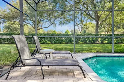 a pair of chairs sitting next to a swimming pool at Mickey's Ranch - 4 bed pool home - Windsor Hills in Orlando