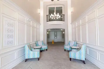 a waiting room with blue chairs and a chandelier at 5min Universal Spacious Condo VC101 in Orlando