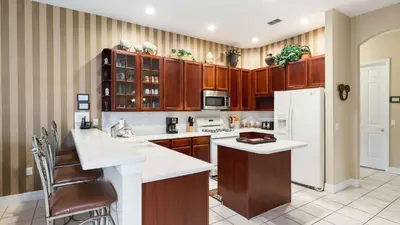 a kitchen with wooden cabinets and a white refrigerator at Closest to Disney in Orlando