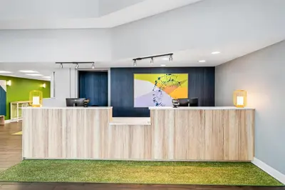 an office lobby with a reception desk with a painting on the wall at Spark by Hilton Orlando near Universal in Orlando