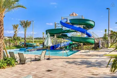 a water slide in a pool at a resort at A - New 4 Bedroom Home - 5 Miles to Disney - Free Water Park - Private Pool in Kissimmee