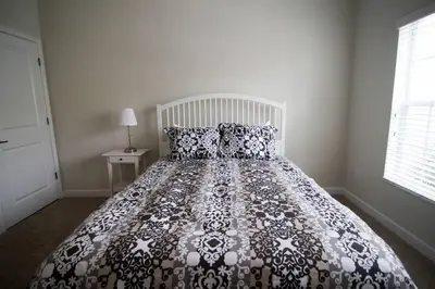 a bed with a black and white comforter in a bedroom at A - New 4 Bedroom Home - 5 Miles to Disney - Free Water Park - Private Pool in Kissimmee