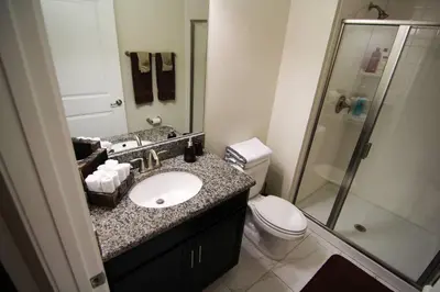 a bathroom with a sink and a toilet and a shower at A - New 4 Bedroom Home - 5 Miles to Disney - Free Water Park - Private Pool in Kissimmee