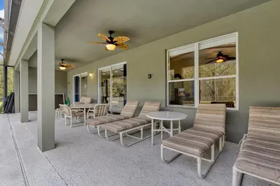 a patio with chairs and tables and a ceiling fan at Mickeys Sunspot - 6 bed Emerald Island Resort pool home in Kissimmee