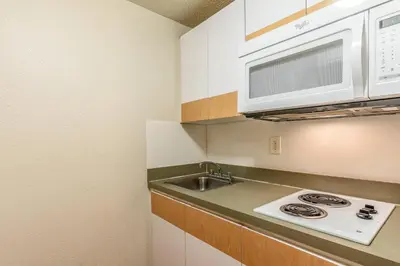 a kitchen with a sink and a microwave at HomeTowne Studios by Red Roof Orlando - Casselberry in Orlando