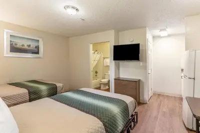a hotel room with two beds and a flat screen tv at HomeTowne Studios by Red Roof Orlando - Casselberry in Orlando