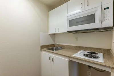 a kitchen with a sink and a microwave at HomeTowne Studios by Red Roof Orlando - Casselberry in Orlando