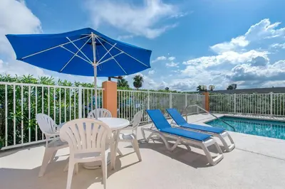 a patio with a table and chairs and a blue umbrella at Comfort Inn Kissimmee-Lake Buena Vista South in Kissimmee