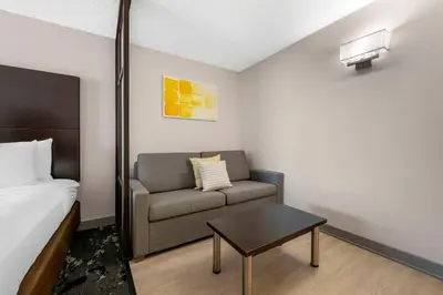 a room with a bed and a couch and a table at City Express by Marriott Orlando International Drive in Orlando