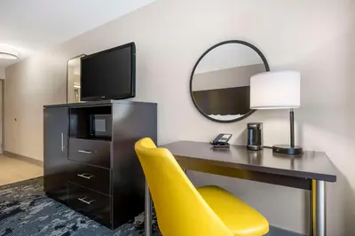 a desk with a yellow chair and a mirror at City Express by Marriott Orlando International Drive in Orlando