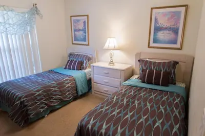 a bedroom with two beds and a dresser with a lamp at Private Pool House With Private Pool, Near All Famous Attractions!!! in Kissimmee
