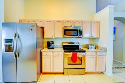a kitchen with a stainless steel refrigerator and cabinets at Fascinating Lake View With Private Pool And Game-Room, Near Disney!! in Kissimmee