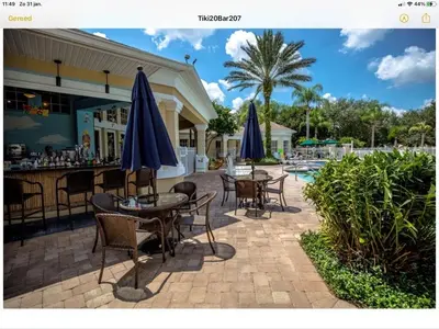 a patio with tables and chairs with umbrellas and a pool at Mickey Holiday Home a Windsor Palms Villa in Kissimmee