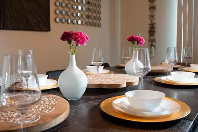 a wooden table with plates and vases with flowers in them at B - New 4 Bedroom Home - 5 Miles to Disney - Free Water Park - Private Pool in Kissimmee