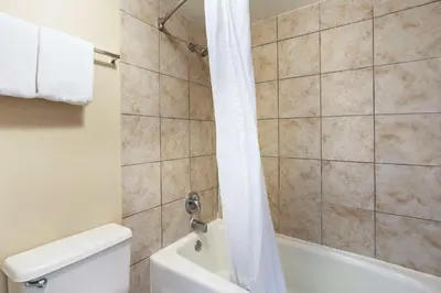 a bathroom with a shower and a toilet and a tub at Suburban Studios International Drive in Orlando