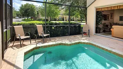 a swimming pool with two chairs and a house at Silver Palms in Kissimmee